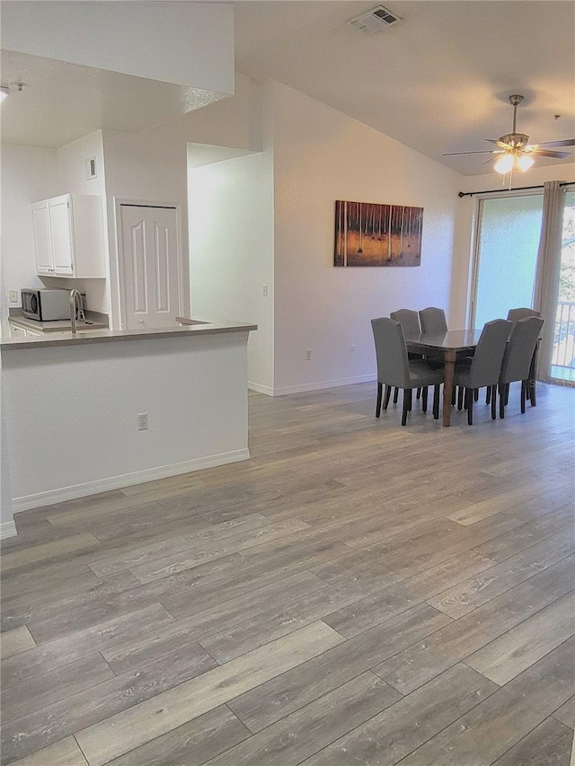 dining room featuring lofted ceiling, ceiling fan, and light hardwood / wood-style flooring