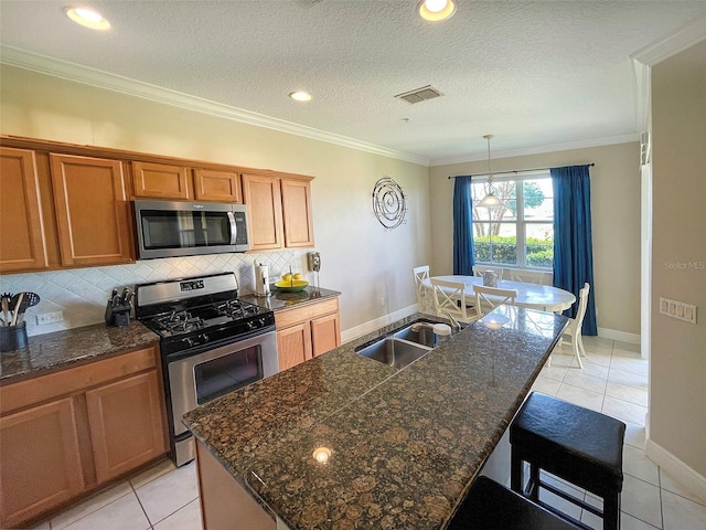 kitchen featuring a center island with sink, crown molding, light tile patterned floors, appliances with stainless steel finishes, and tasteful backsplash