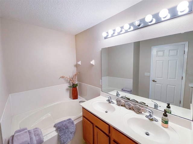 bathroom with vanity, a textured ceiling, and a tub to relax in