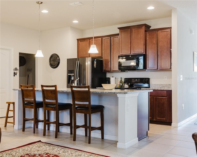 kitchen featuring a kitchen breakfast bar, a kitchen island, black appliances, and decorative light fixtures