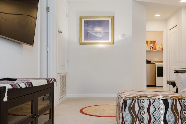 bedroom with washer and clothes dryer and light colored carpet