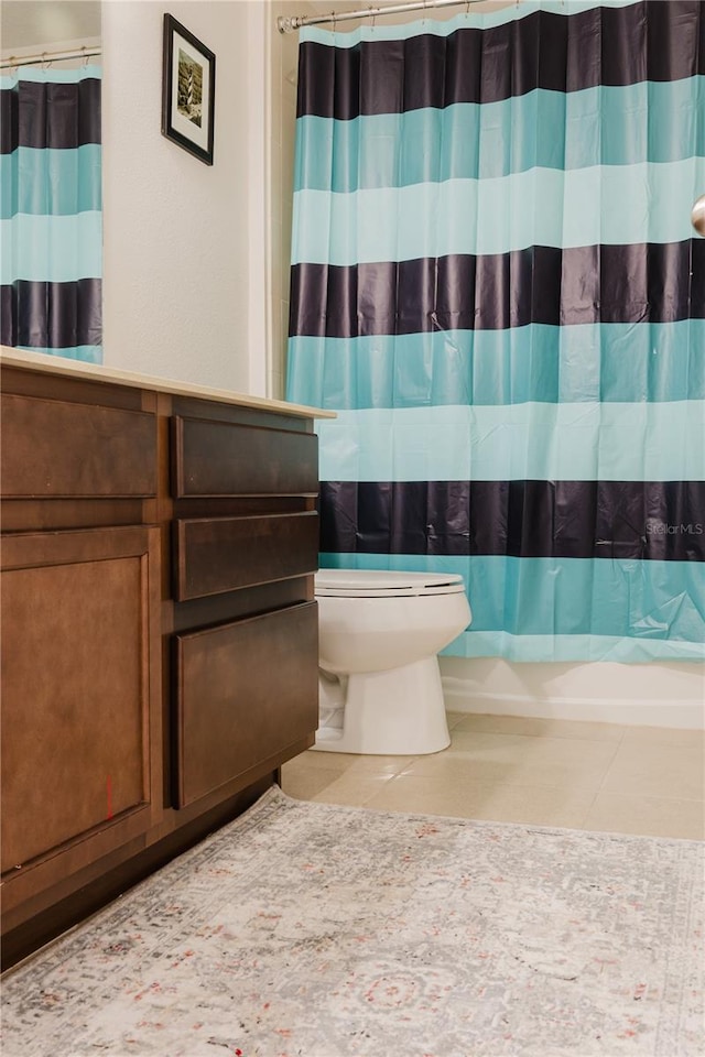 bathroom featuring tile patterned floors, curtained shower, and toilet