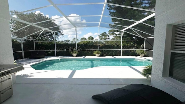 view of pool with glass enclosure and a patio