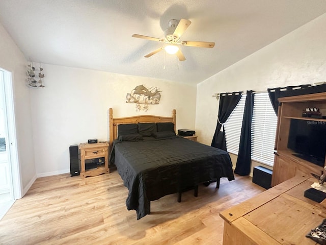 bedroom with ceiling fan, light hardwood / wood-style floors, a textured ceiling, and vaulted ceiling