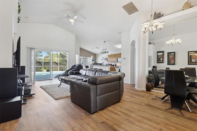 living room with hardwood / wood-style flooring, ceiling fan with notable chandelier, and high vaulted ceiling