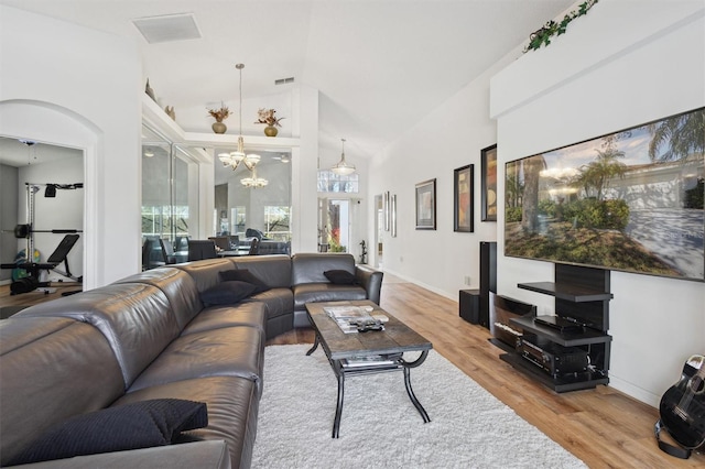 living room featuring an inviting chandelier, wood-type flooring, and high vaulted ceiling