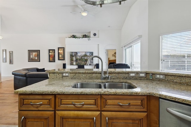 kitchen featuring vaulted ceiling, dishwasher, sink, ceiling fan, and light stone countertops