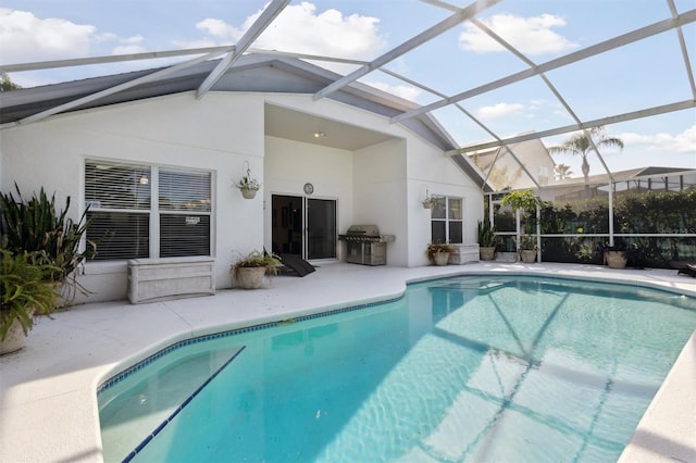 view of swimming pool with a grill, a patio, and glass enclosure