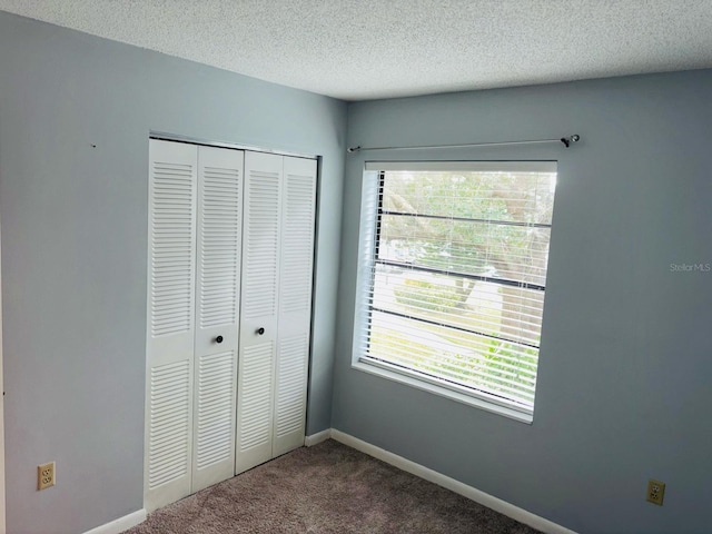 unfurnished bedroom with multiple windows, a closet, carpet floors, and a textured ceiling