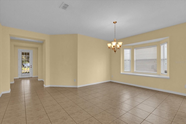 tiled empty room with an inviting chandelier