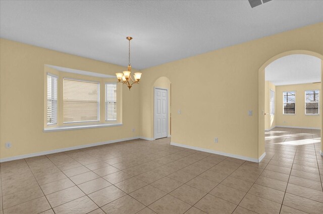 tiled empty room with a notable chandelier