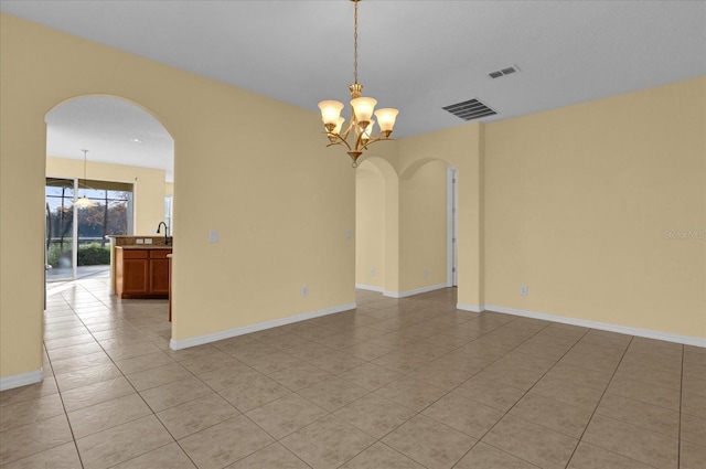 tiled empty room featuring sink and a chandelier