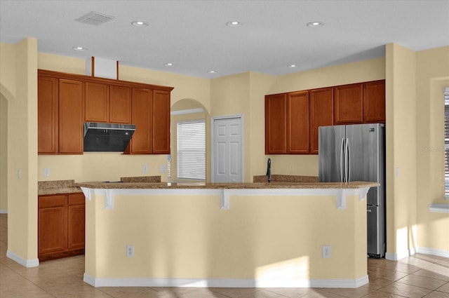 kitchen featuring a breakfast bar, a kitchen island with sink, and range hood