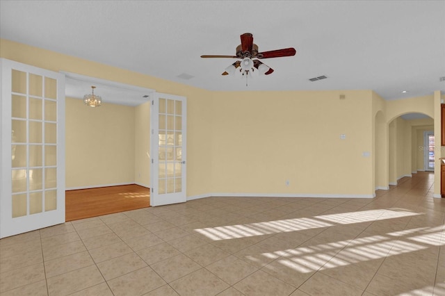 unfurnished room featuring french doors, light tile patterned flooring, and ceiling fan with notable chandelier