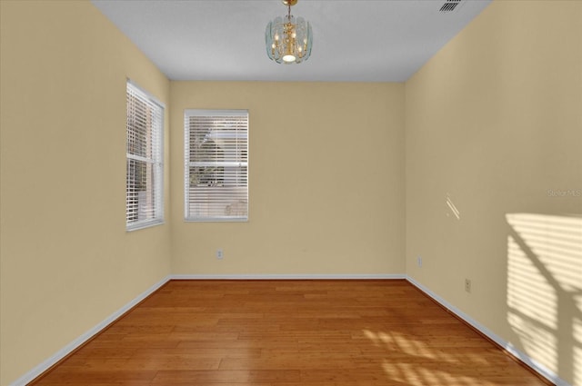 unfurnished room with light hardwood / wood-style flooring and a notable chandelier