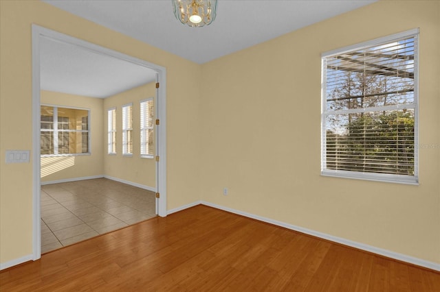 spare room with an inviting chandelier and light hardwood / wood-style flooring