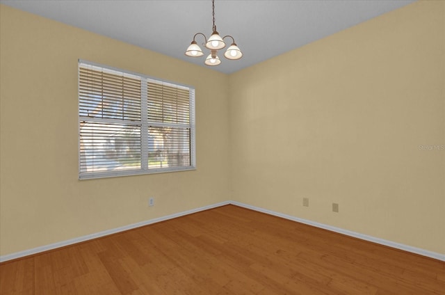 unfurnished room with hardwood / wood-style flooring and a notable chandelier