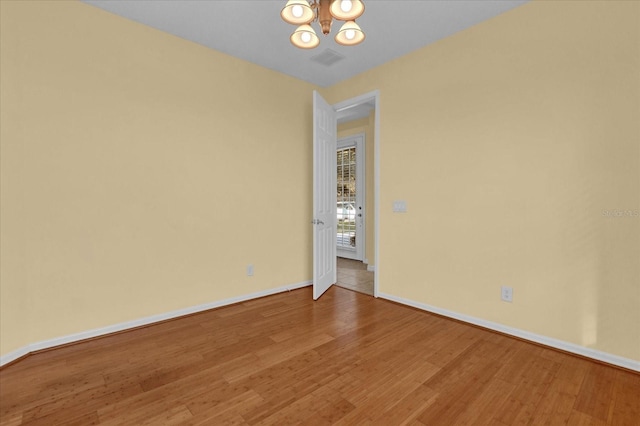 spare room with wood-type flooring and a chandelier