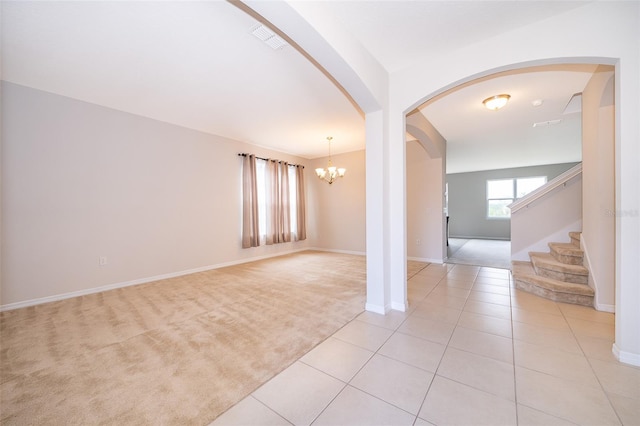 carpeted spare room featuring an inviting chandelier