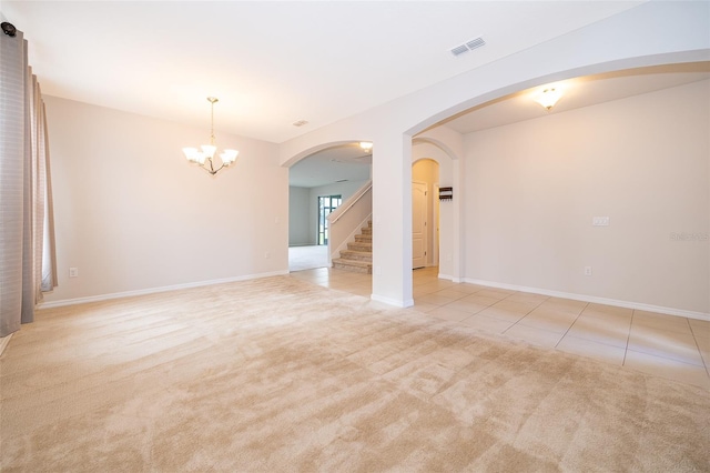 spare room featuring light tile patterned flooring and a notable chandelier