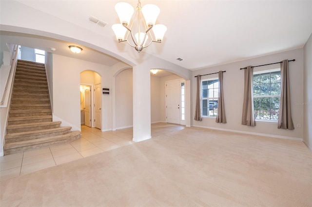 carpeted empty room with a notable chandelier