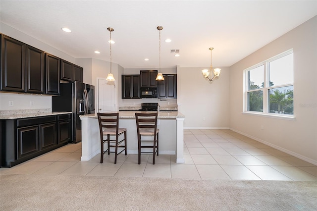 kitchen with light tile patterned floors, light stone counters, pendant lighting, and black appliances