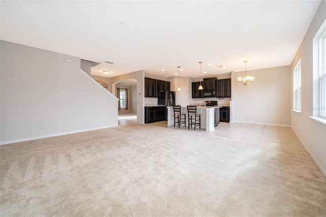 unfurnished living room with light carpet and an inviting chandelier