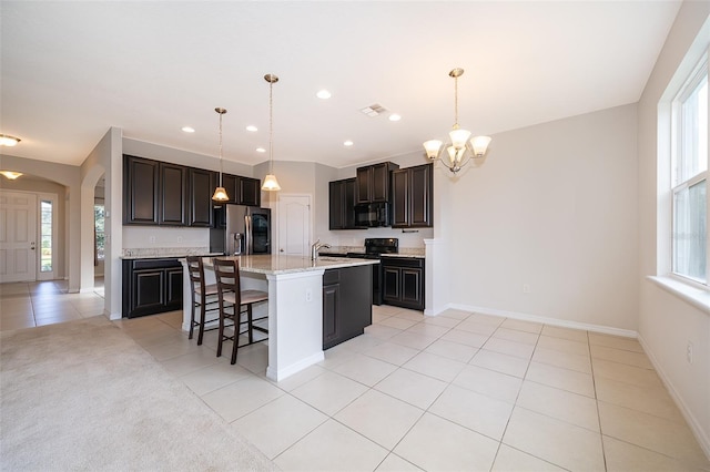 kitchen with stainless steel fridge, light tile patterned flooring, a healthy amount of sunlight, and a kitchen island with sink