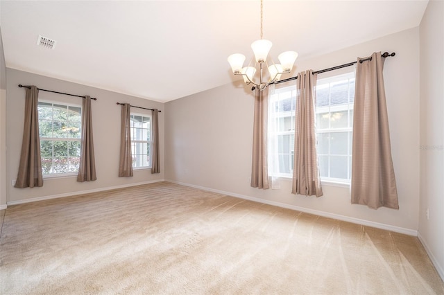 carpeted empty room featuring an inviting chandelier