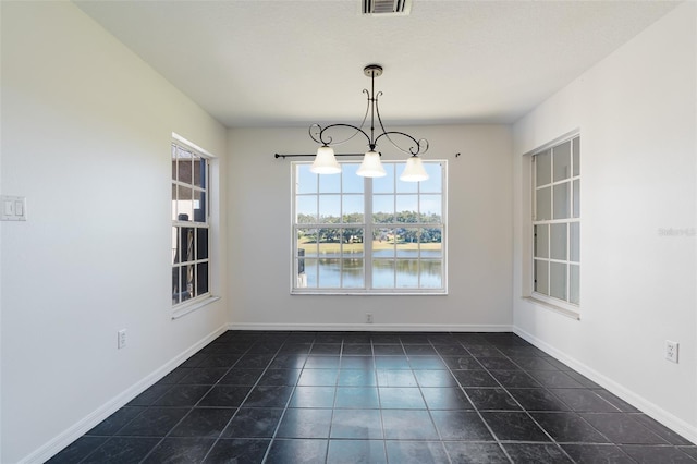 unfurnished dining area with a water view and dark tile patterned floors