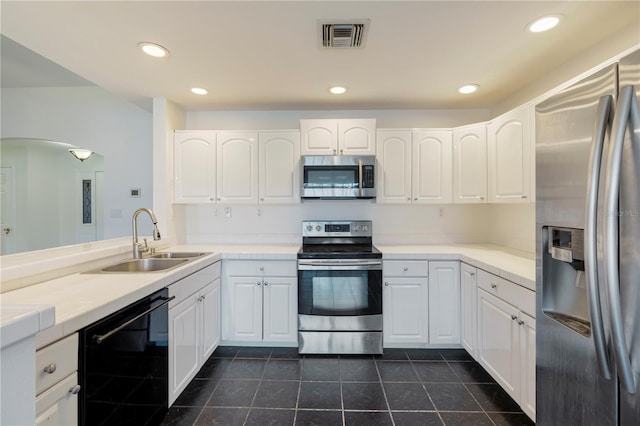 kitchen with stainless steel appliances, dark tile patterned floors, sink, and white cabinets