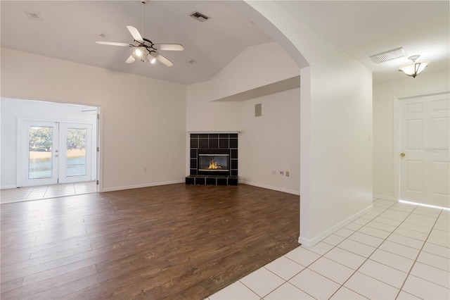 unfurnished living room featuring ceiling fan, lofted ceiling, light wood-type flooring, and a fireplace