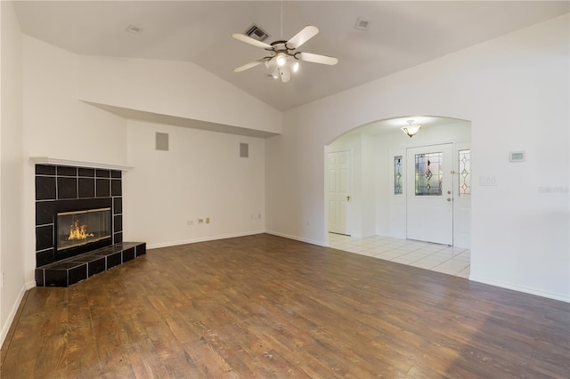 unfurnished living room featuring ceiling fan, lofted ceiling, a fireplace, and light wood-type flooring