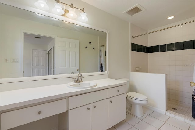 bathroom with vanity, tile patterned flooring, toilet, and tiled shower