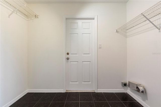 laundry room featuring electric dryer hookup and dark tile patterned floors