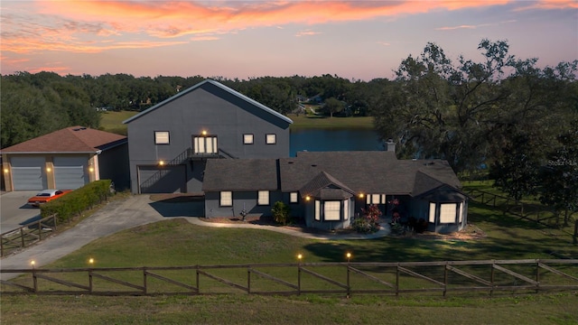 view of front facade featuring a garage, a lawn, and a water view