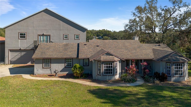 rear view of property with a garage and a lawn