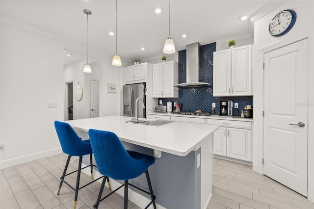 kitchen with white cabinets, stainless steel appliances, an island with sink, and wall chimney exhaust hood