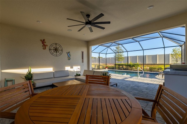 view of patio featuring ceiling fan, an outdoor living space, and glass enclosure