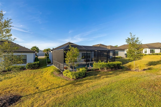 rear view of house featuring a lanai, a swimming pool, and a lawn