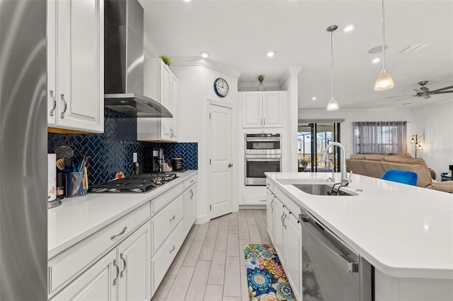 kitchen with wall chimney exhaust hood, sink, white cabinetry, a center island with sink, and stainless steel appliances