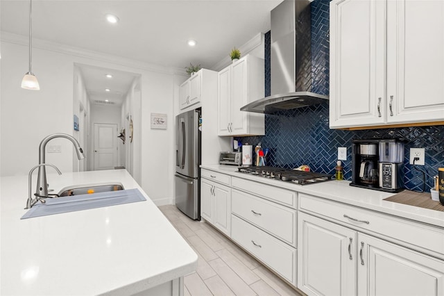 kitchen with appliances with stainless steel finishes, sink, white cabinets, and wall chimney exhaust hood