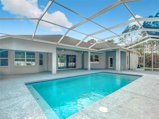 view of swimming pool with glass enclosure, ceiling fan, and a patio area