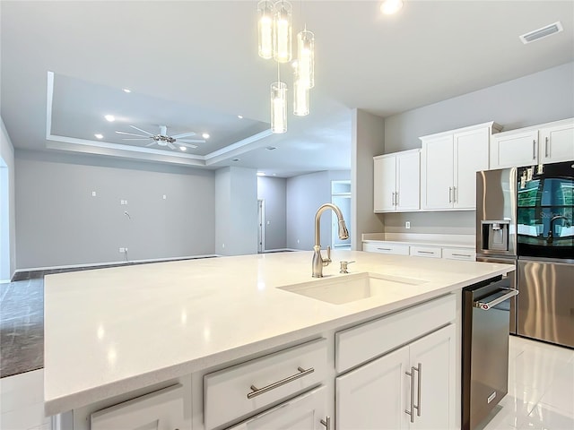 kitchen with white cabinets, sink, and a tray ceiling