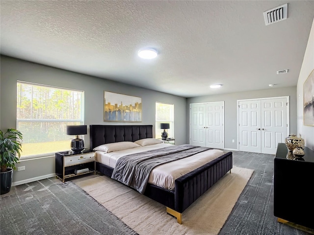 bedroom with multiple closets, a textured ceiling, and hardwood / wood-style flooring