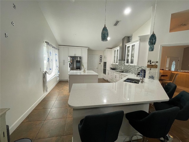 kitchen featuring kitchen peninsula, sink, vaulted ceiling, white cabinetry, and a breakfast bar area