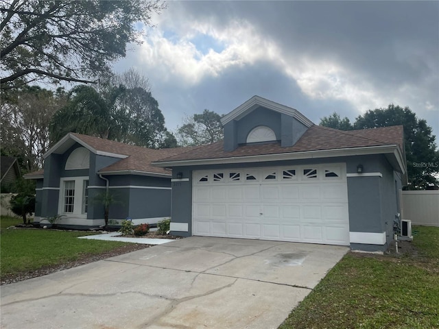 single story home with stucco siding, an attached garage, concrete driveway, and a front lawn