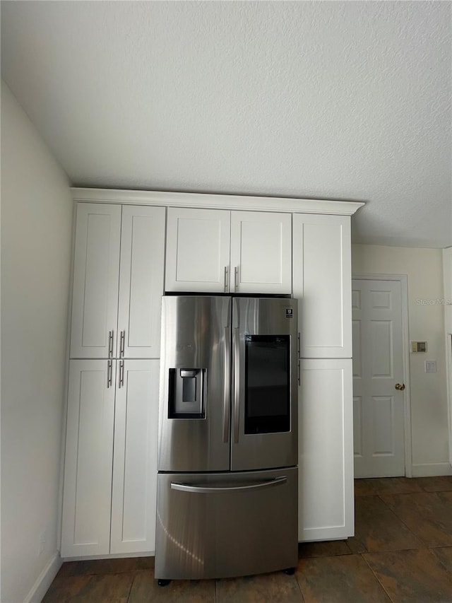 kitchen with baseboards, a textured ceiling, stainless steel fridge with ice dispenser, and white cabinetry