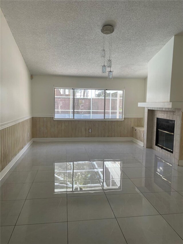 unfurnished living room with wainscoting, a textured ceiling, and a healthy amount of sunlight