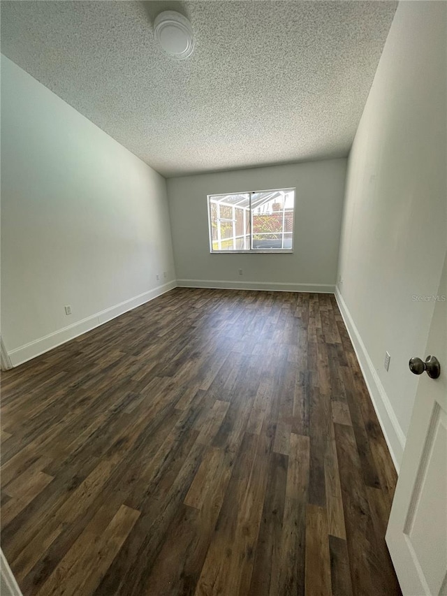 empty room with baseboards, a textured ceiling, and dark wood-style flooring